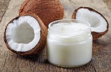 two coconuts and coconut oil in jar without lid